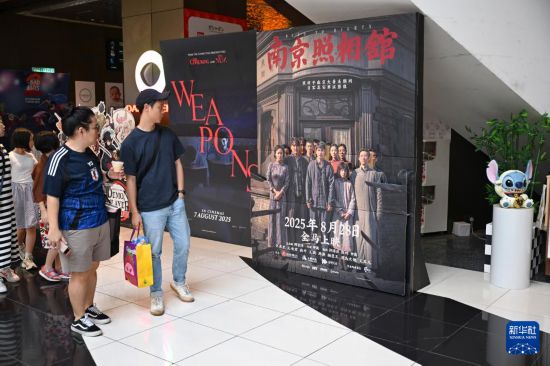 8月24日,在马来西亚吉隆坡,民众观看《南京照相馆》电影海报。新华社记者 程一恒 摄